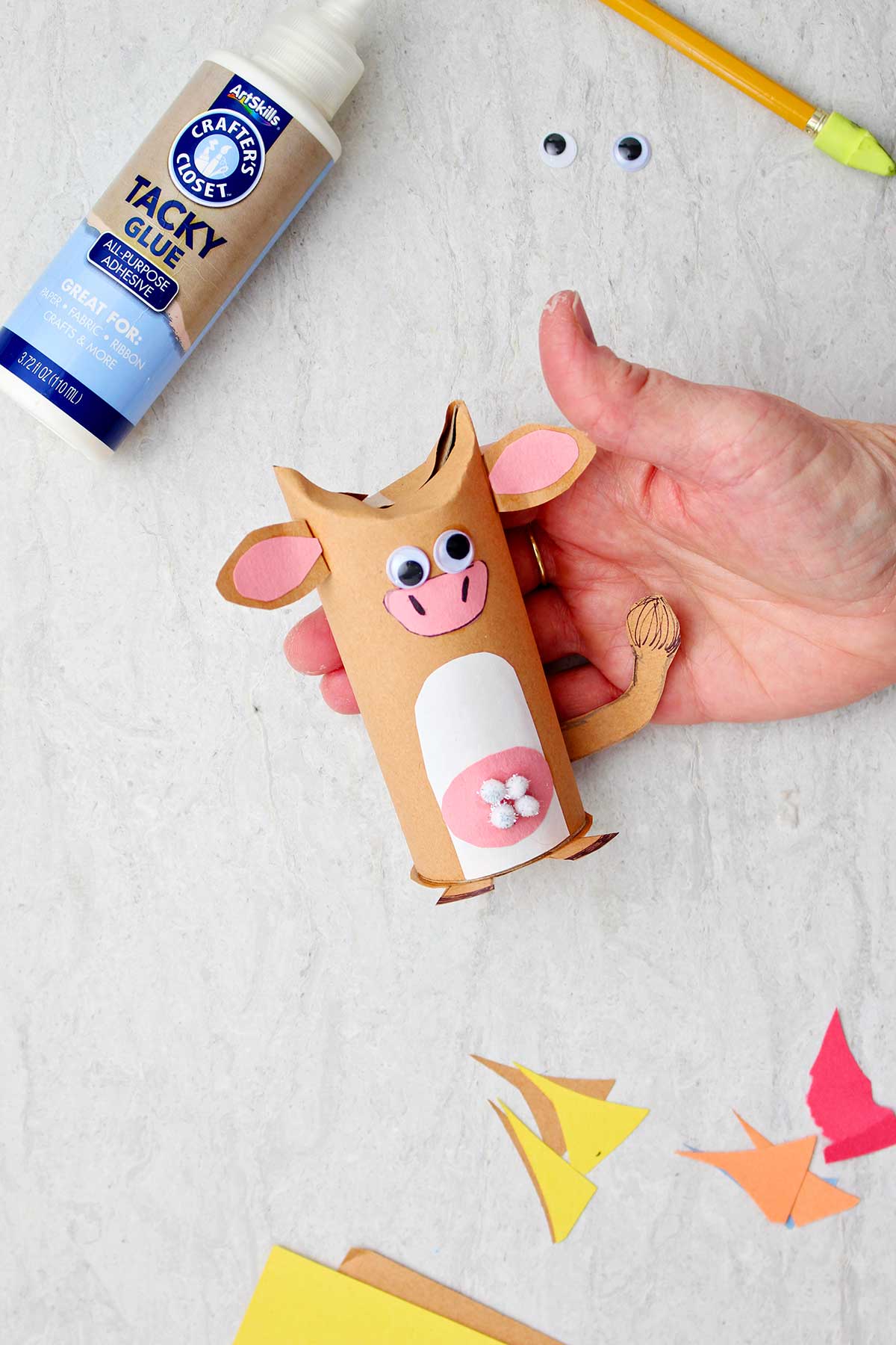 Hand holding cow toilet paper roll animal.