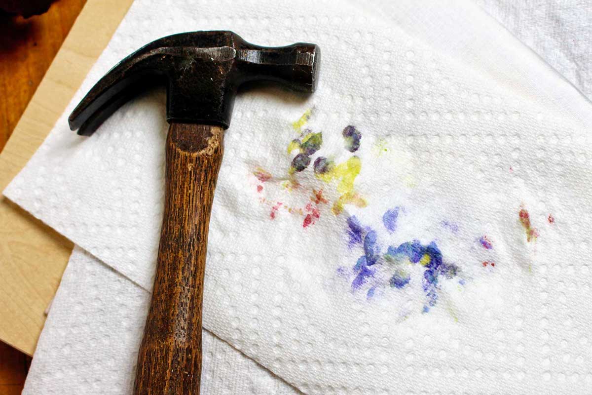 A hammer resting on a stack of paper towels used in flower hammering.