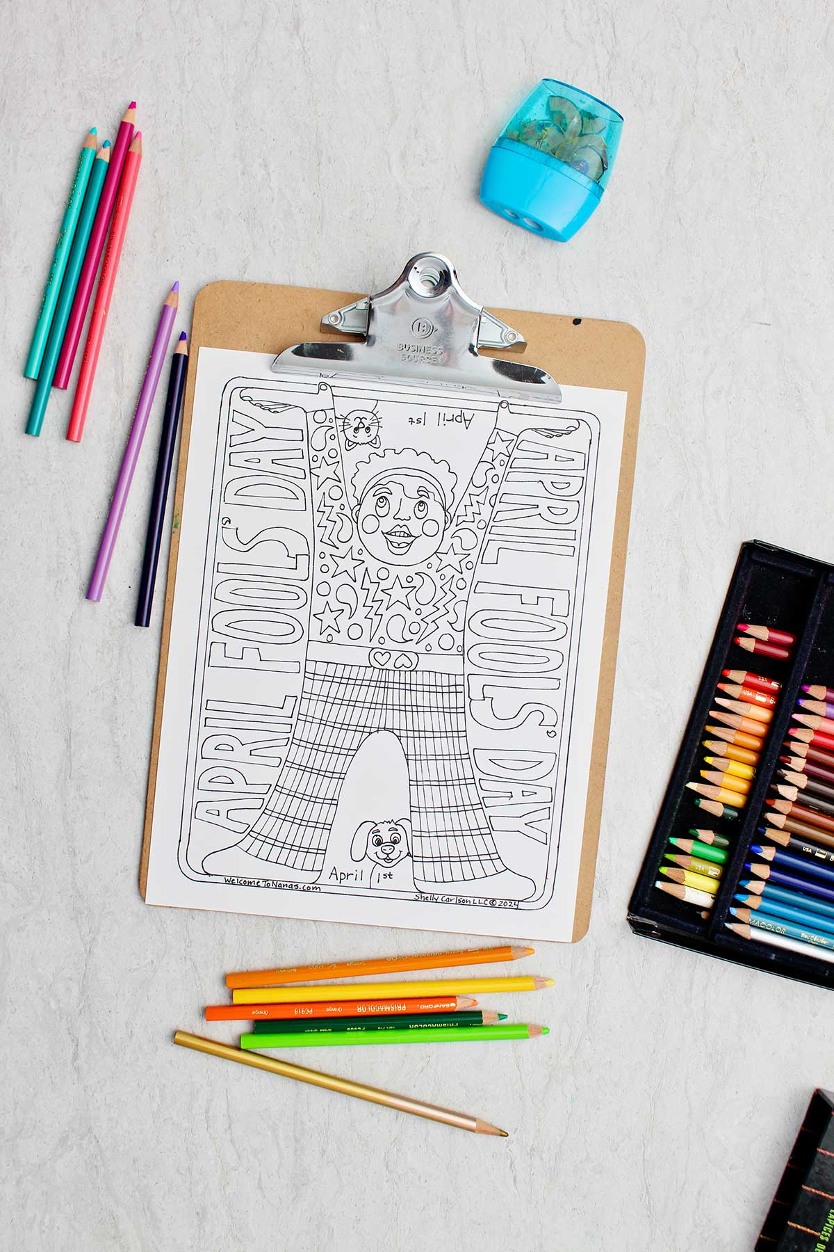 April Fools Day Coloring Page on clip board with colored pencils around.