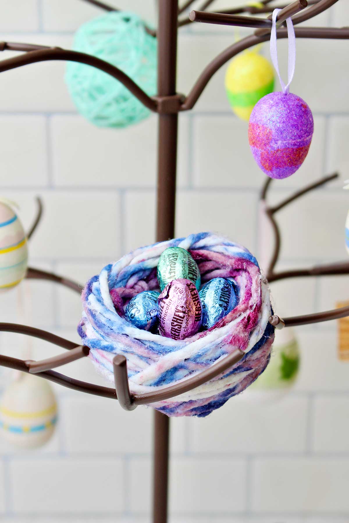 A bird nest made of colorful variegated yarn with Hershey chocolates inside.