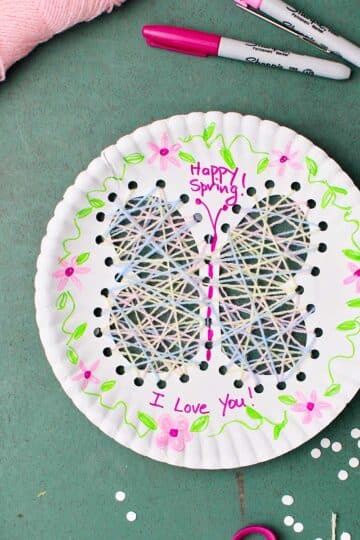 Completed Paper Plate String Art of a butterfly with flower decorations and "Happy Spring" "I Love You!" written on the plate.