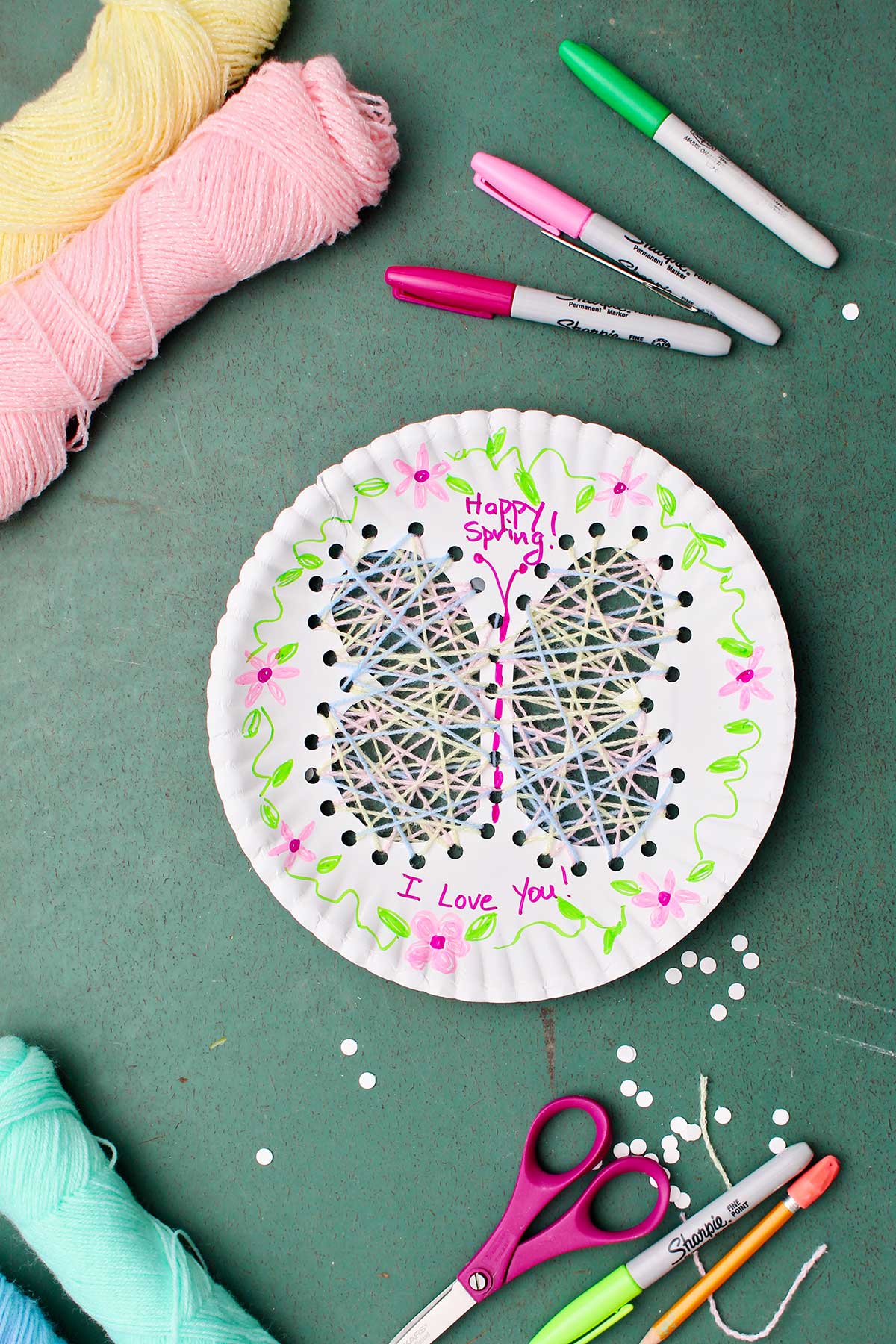 Completed Paper Plate String Art of a butterfly with flower decorations and "Happy Spring" "I Love You!" written on the plate.