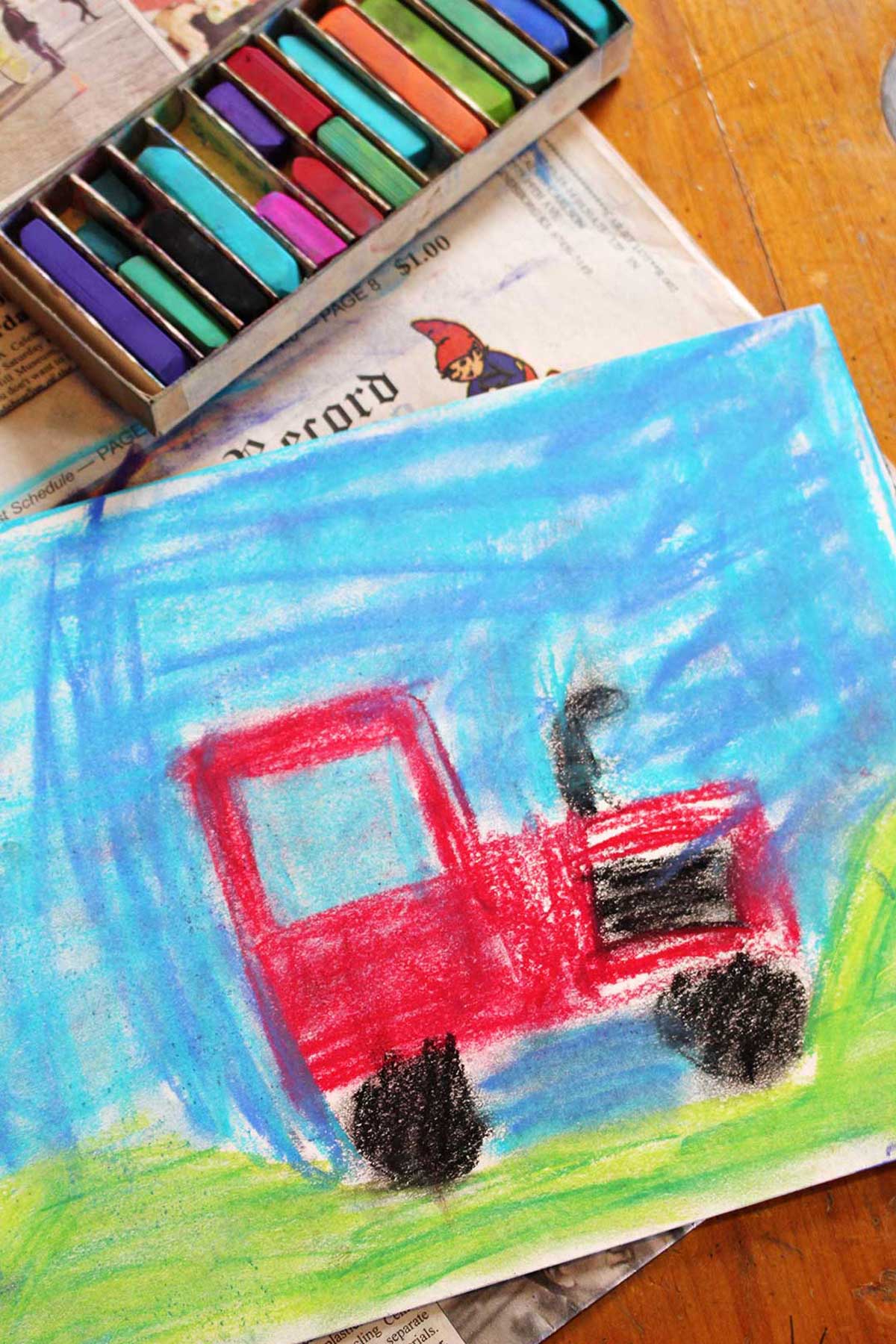 Drawing of a red tractor with pastels on a kitchen table.