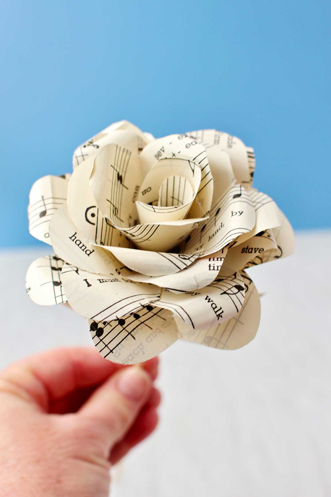 Hand holding completed Book Page Rose made from sheet music.