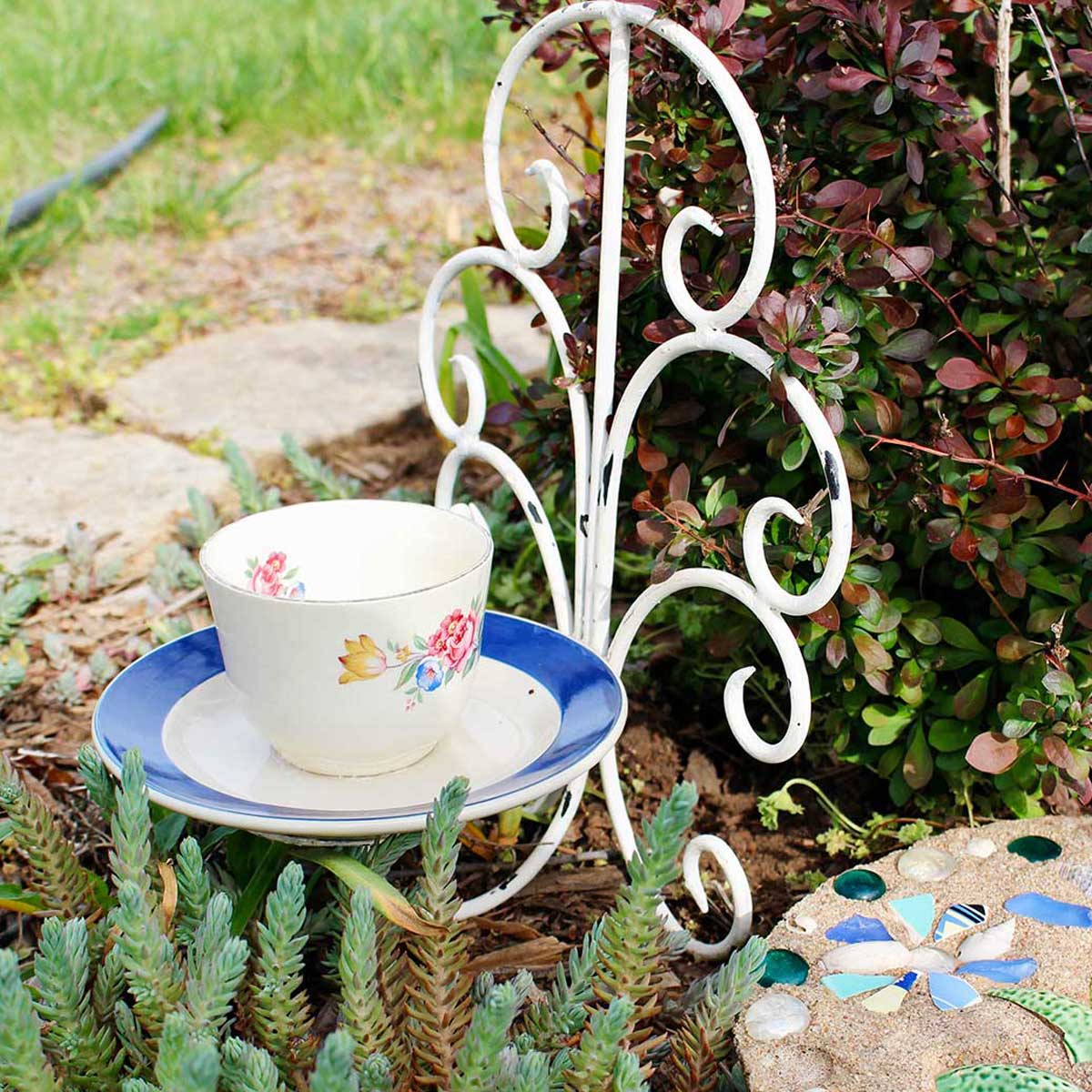 Teacup Bird Feeder resting in a garden.