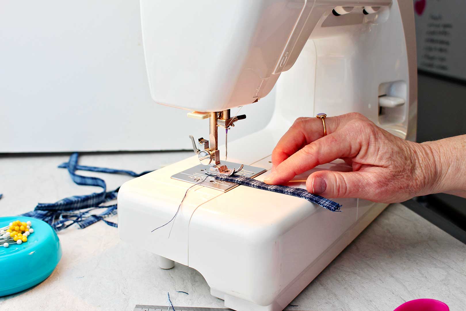Hand sewing small strip of fabric on sewing machine.