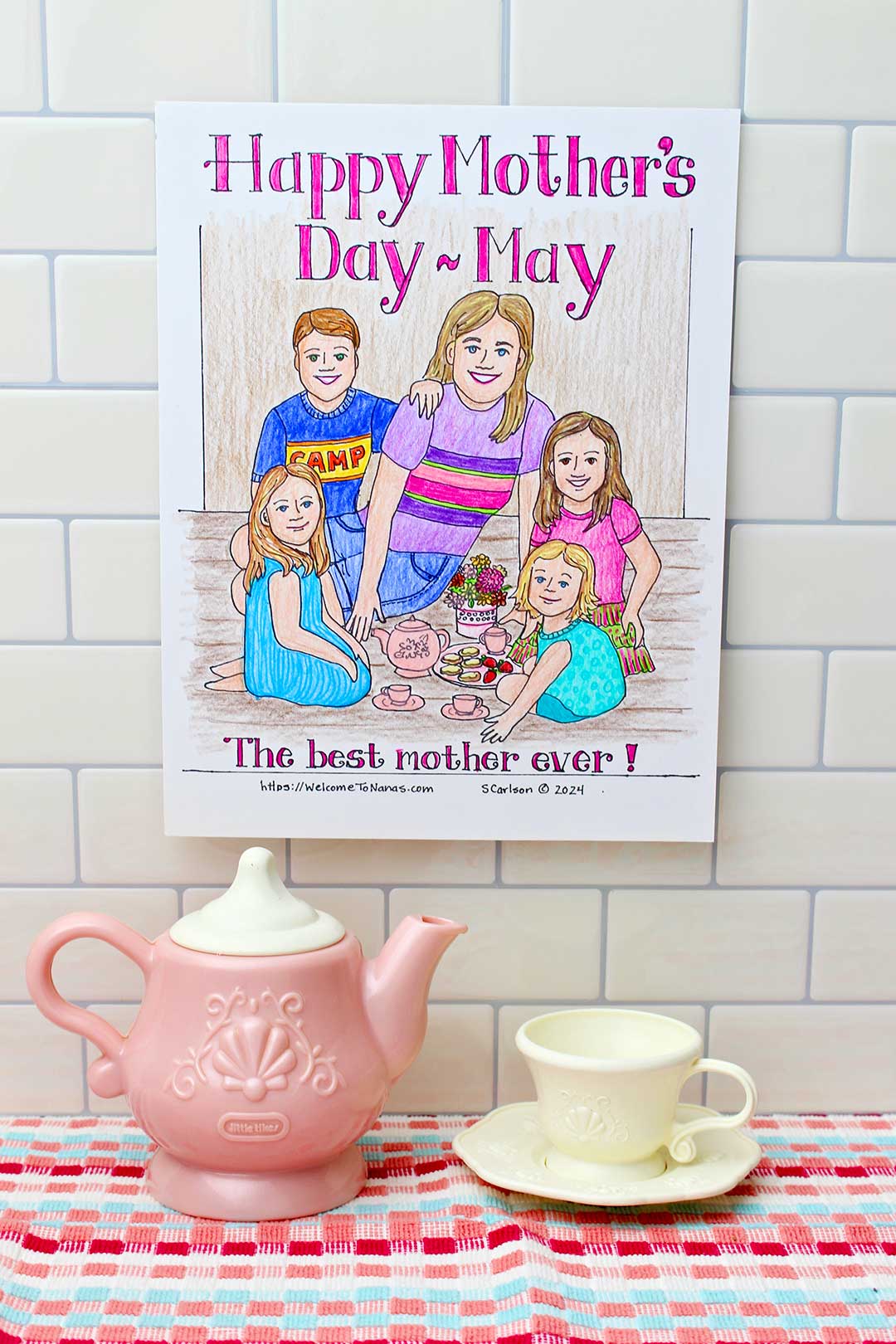 Completed Mother's Day Coloring page attached to tile backsplash with plastic tea set under.
