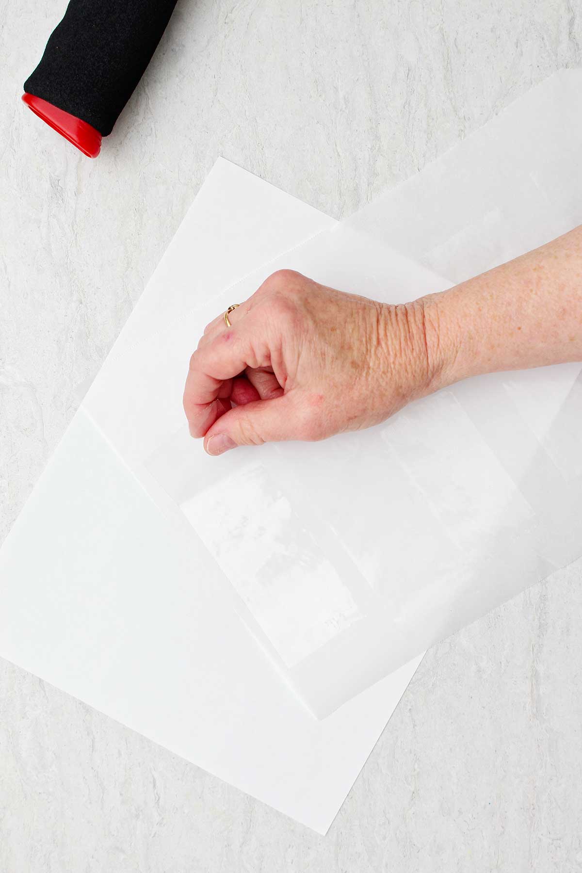 Hand placing packing tape pieces on to a piece of parchment paper.