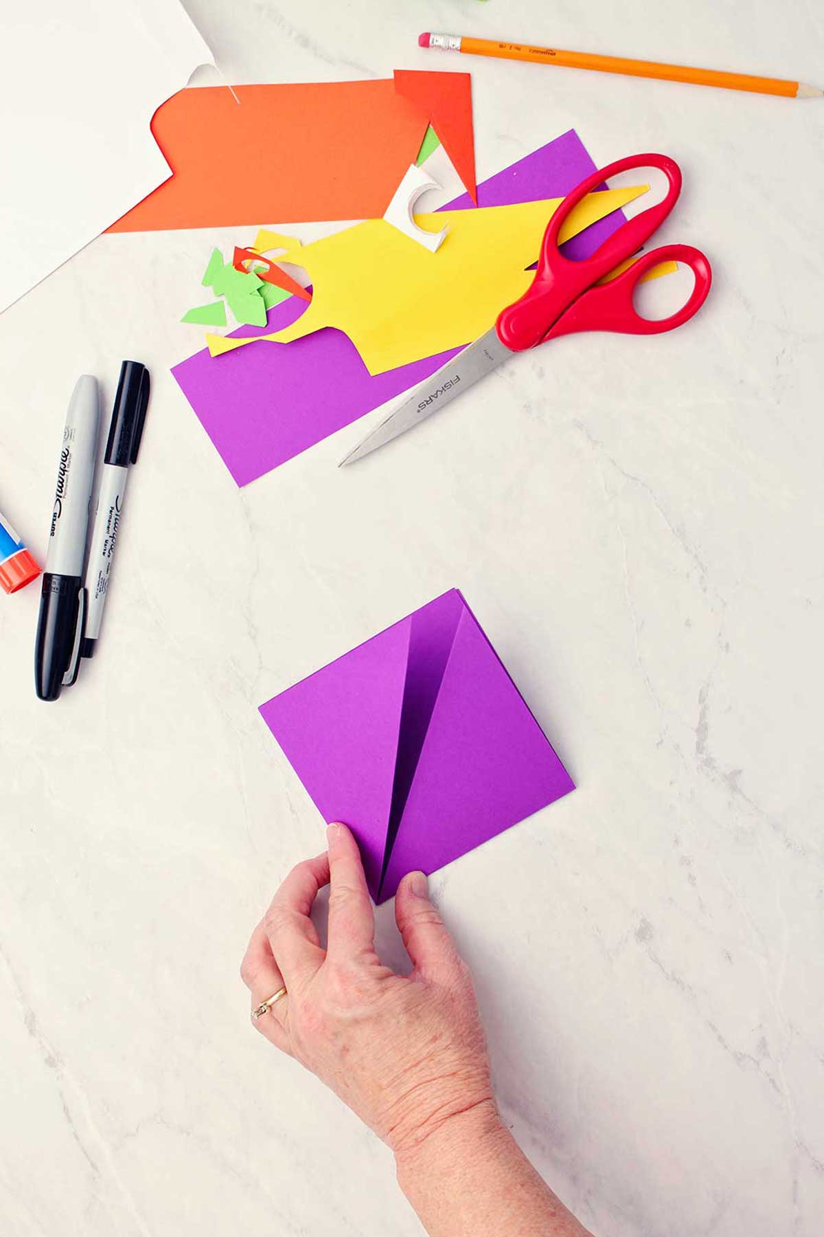 Square piece of purple paper with folds to make to triangle flaps.