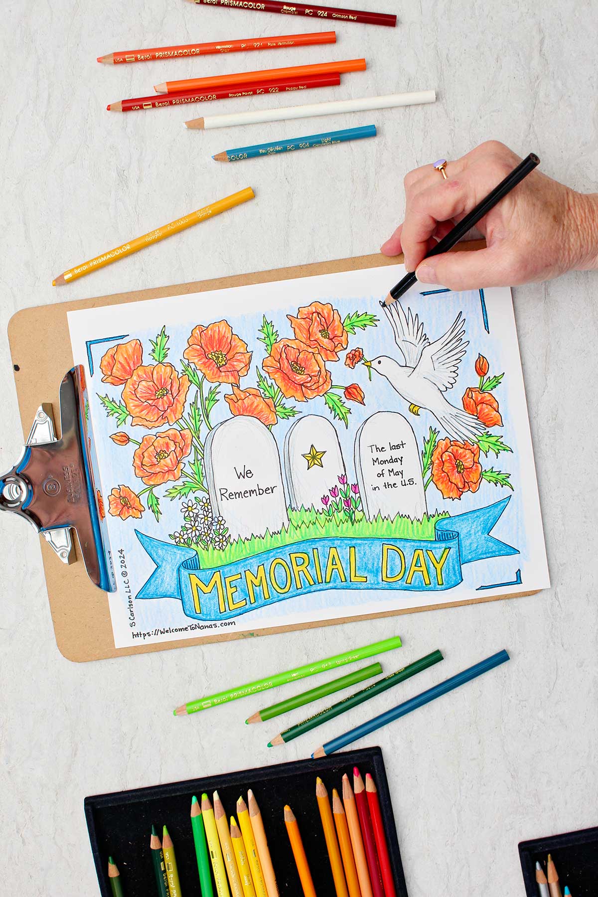 Hand coloring boarder on Memorial Day Coloring Page blue with colored pencils near by.