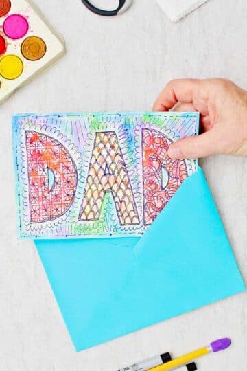 Doodle card for Dad made with watercolors and sharpie. Hand placing the card into a blue envelope.