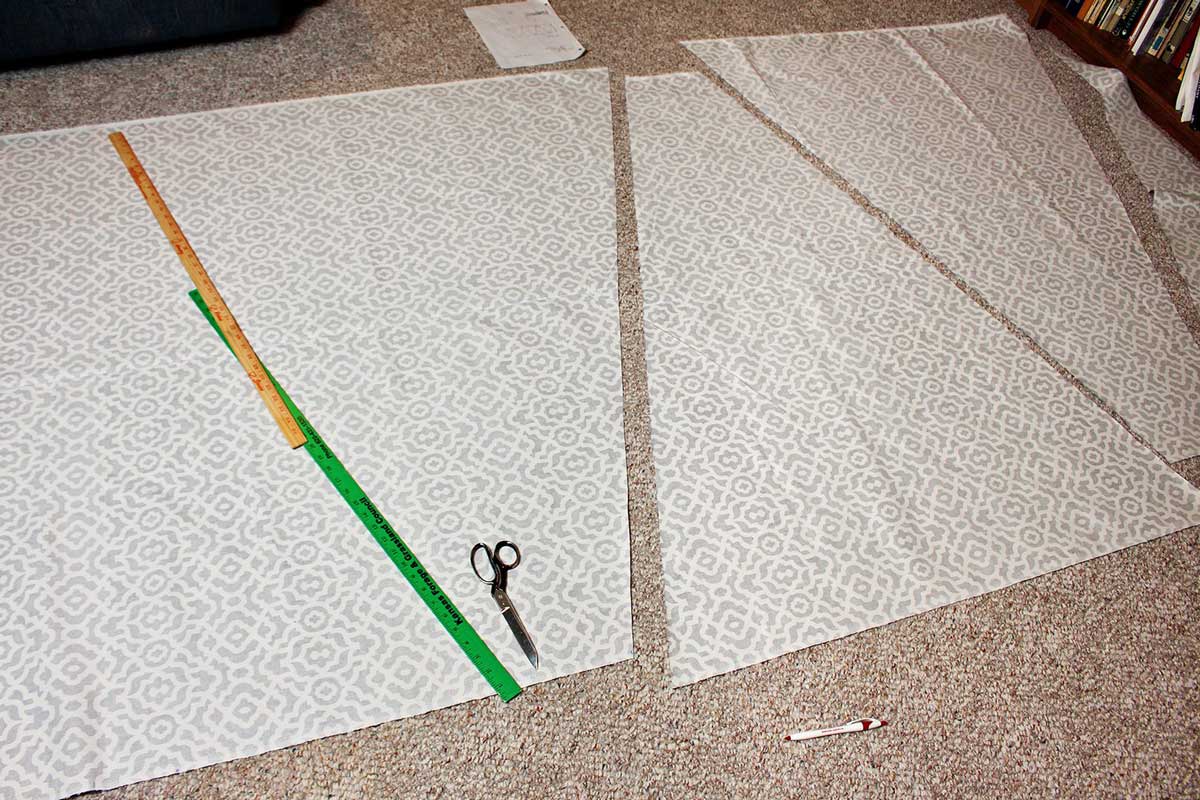 Triangle panels for a DIY Teepee Tent for Kids being cut from fabric with a fabric scissors, measured with a yard stick.