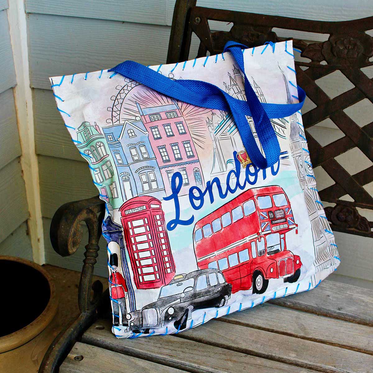 Cushion made from reusable shopping bag with scenes of London on it sitting on a bench.