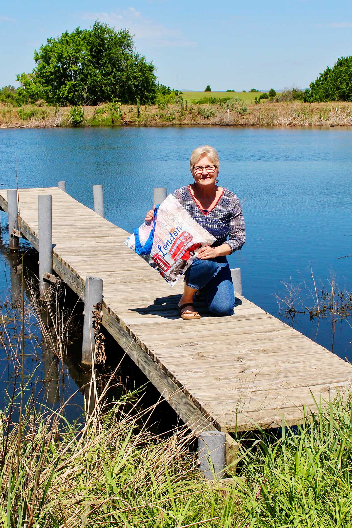 Nana on a dock holding her sit upon cushion made from a reusable shopping bag.