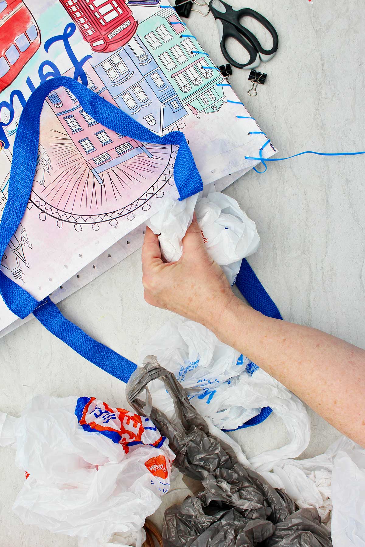 Person stuffing plastic shopping bags in the top open end of cushion.