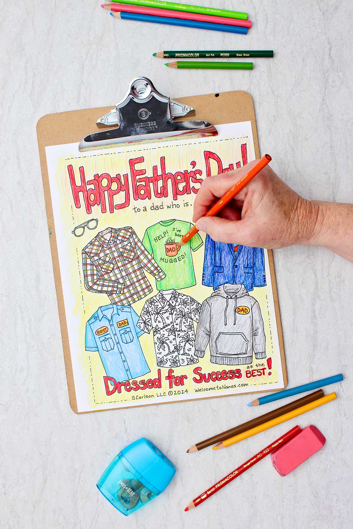 Hand coloring mug on shirt orange on Father's Day coloring page with colored pencils and pencil sharpener near by.