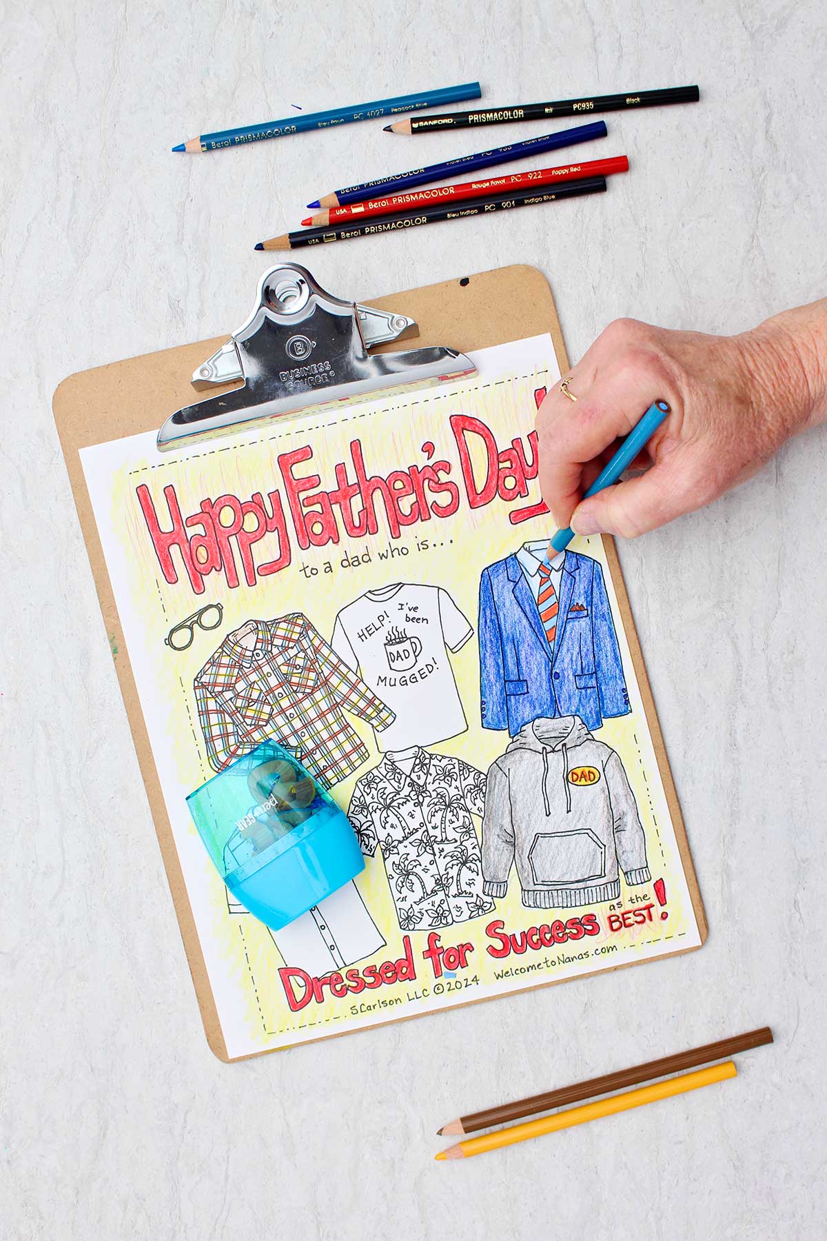 Hand coloring a suit jacket blue on Father's Day coloring page with colored pencils and pencil sharpener near by.