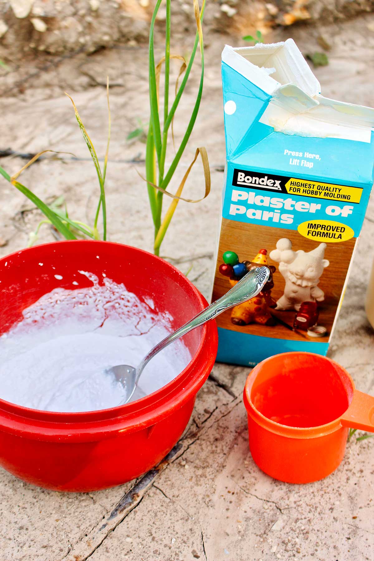 Plaster of Paris in a bowl with a spoon and a measuring cup outside.