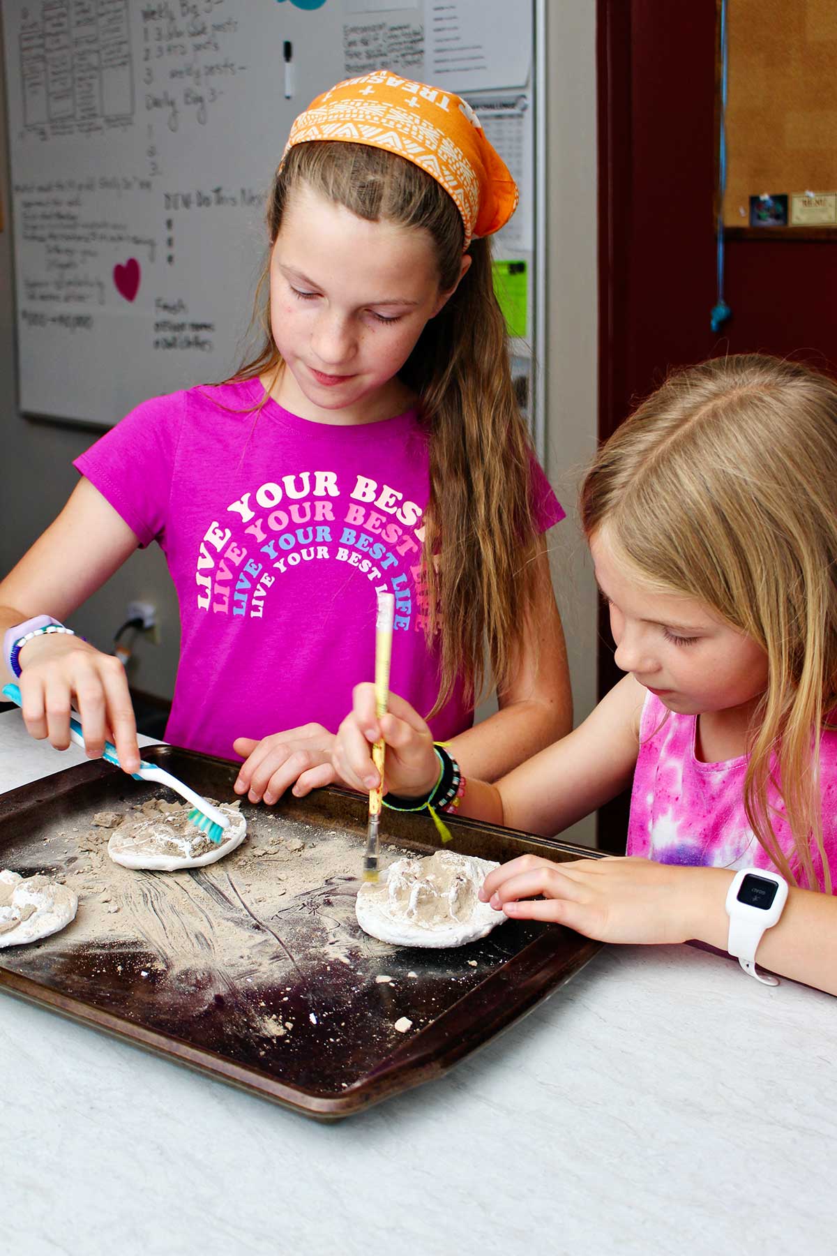 Two young girls brushing off dirt from their animal track plaster casts.