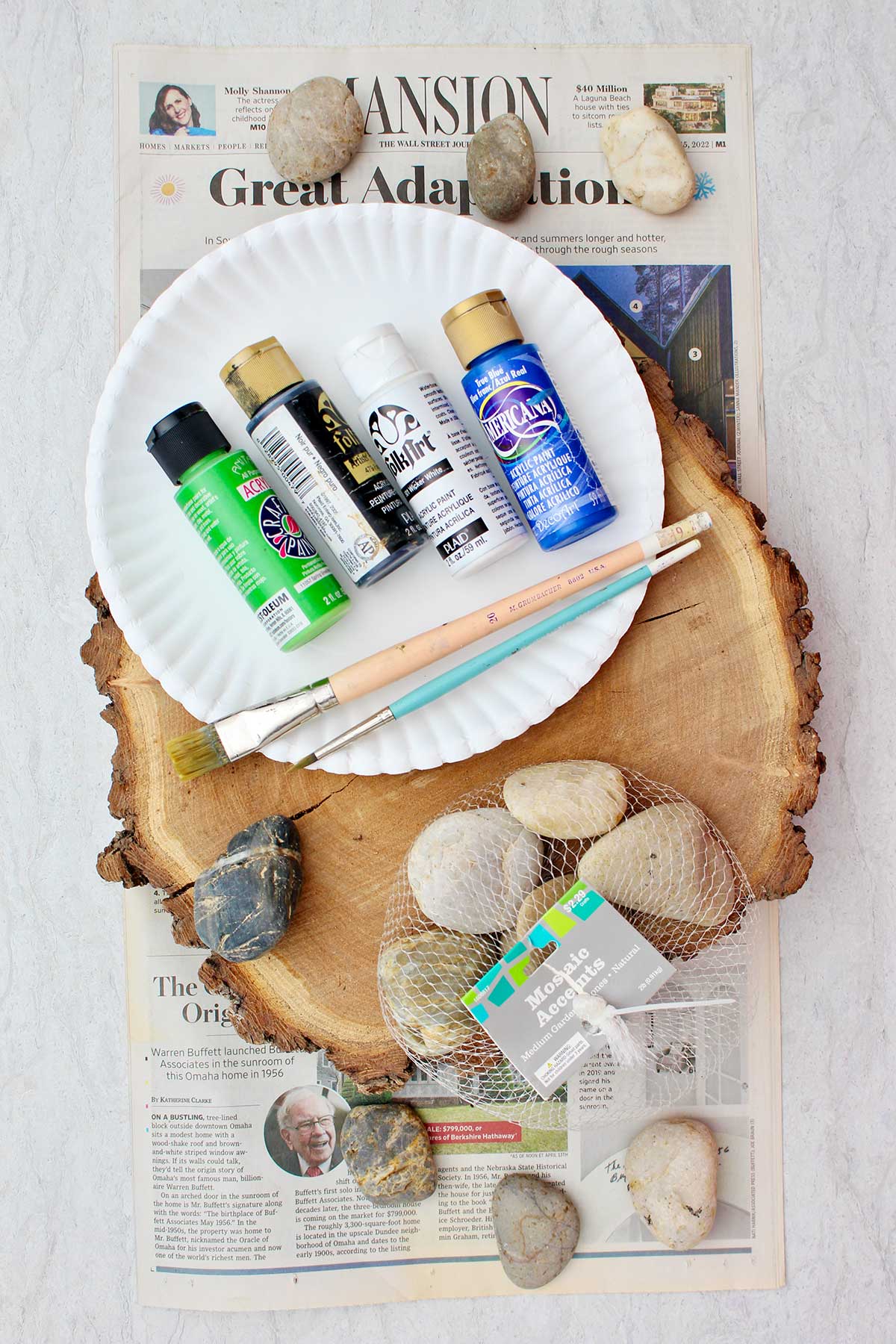 Supplies to make tic tac toe board with painted rocks. Acrylic paint, circular slice of wood, flat rocks, and paint brushes.