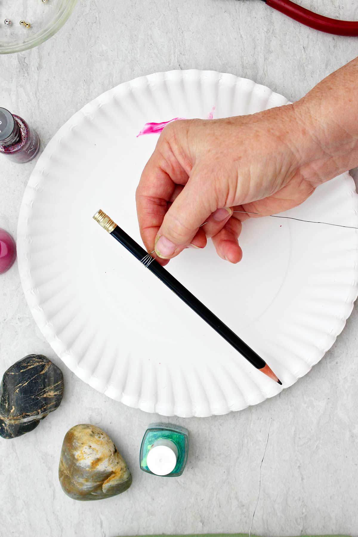 Person wrapping wire around a pencil.