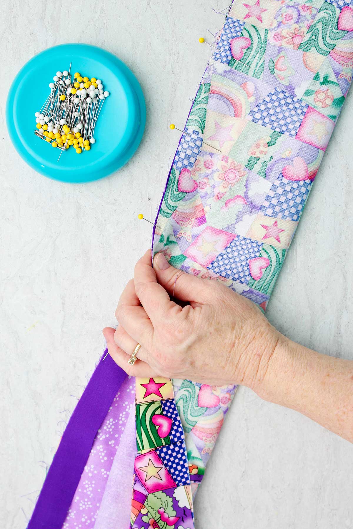 Person pinning right sides of the fabric to the pillowcase together with straight pins.