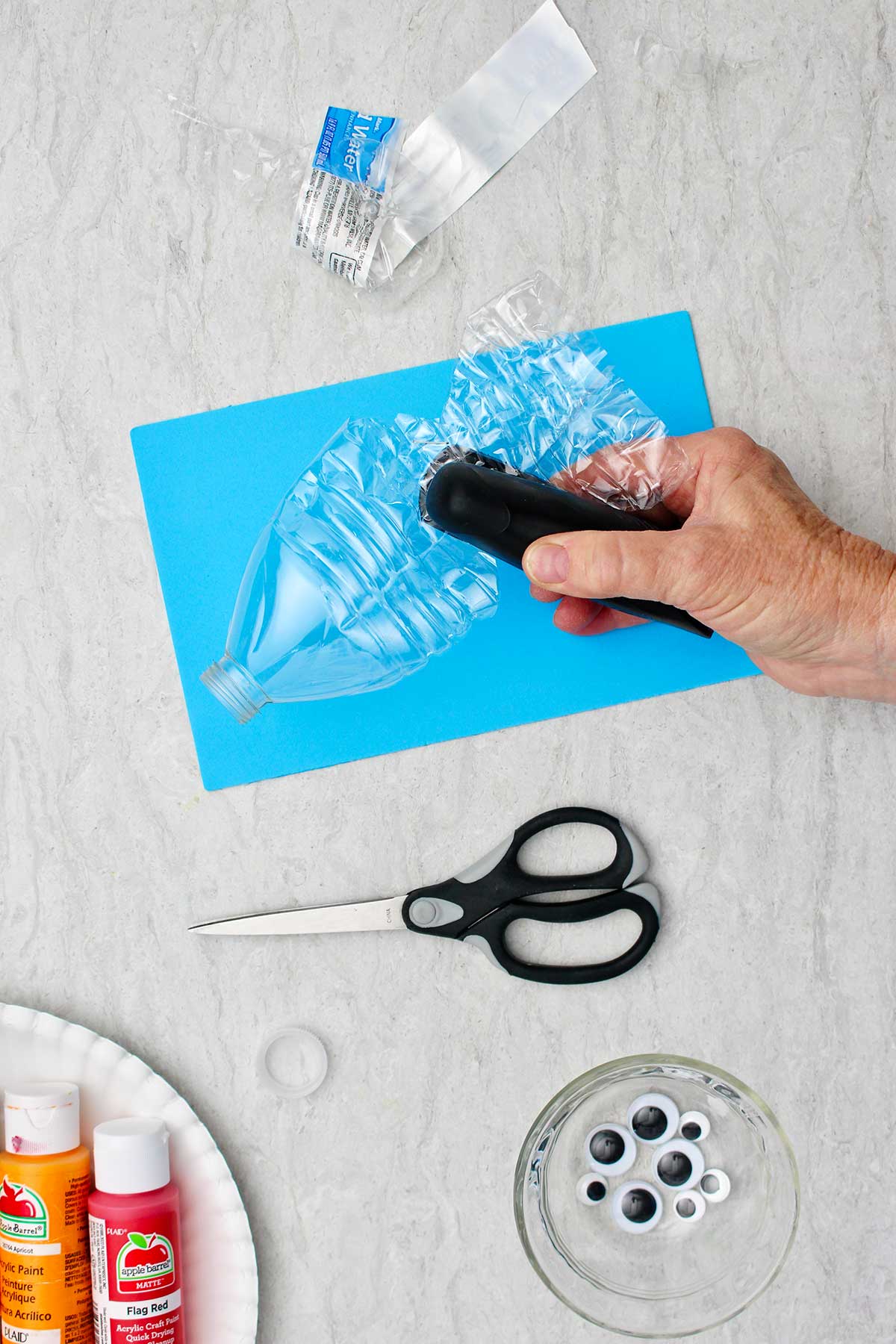 Person stapling inner part of the cut water bottle to make fish.