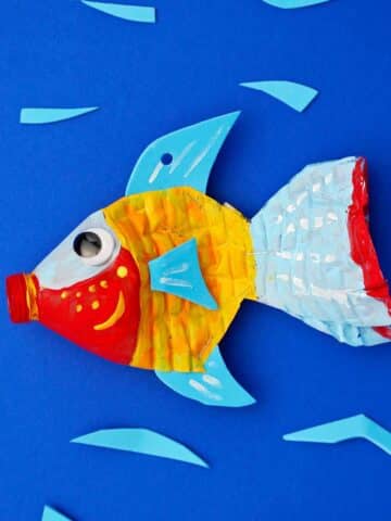 Plastic bottle fish painted red, yellow, blue and orange against a blue backdrop.