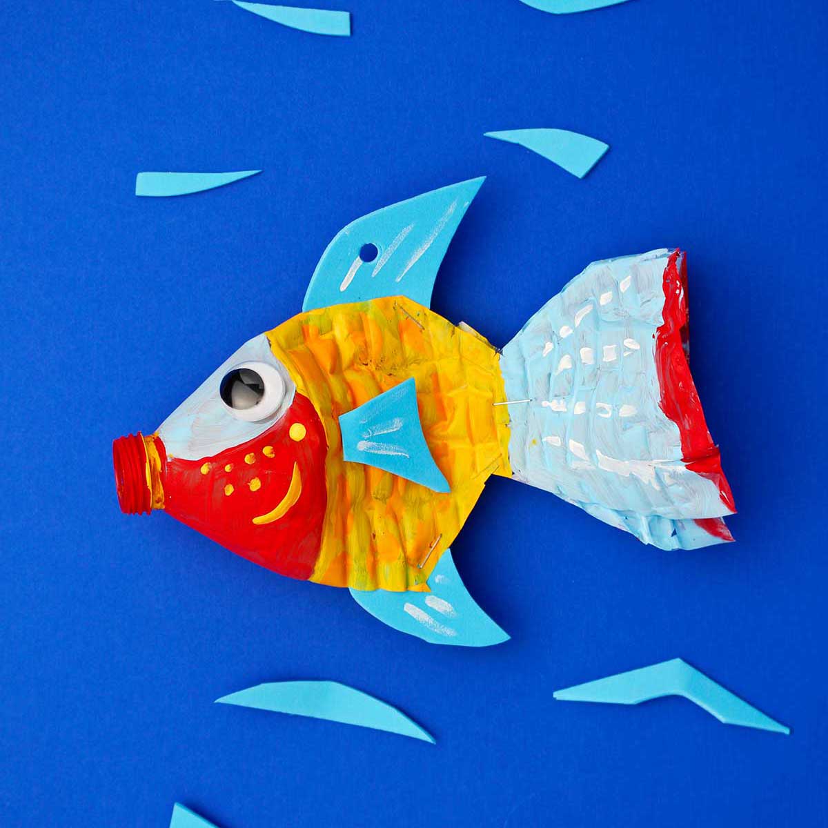 Plastic bottle fish painted red, yellow, blue and orange against a blue backdrop.