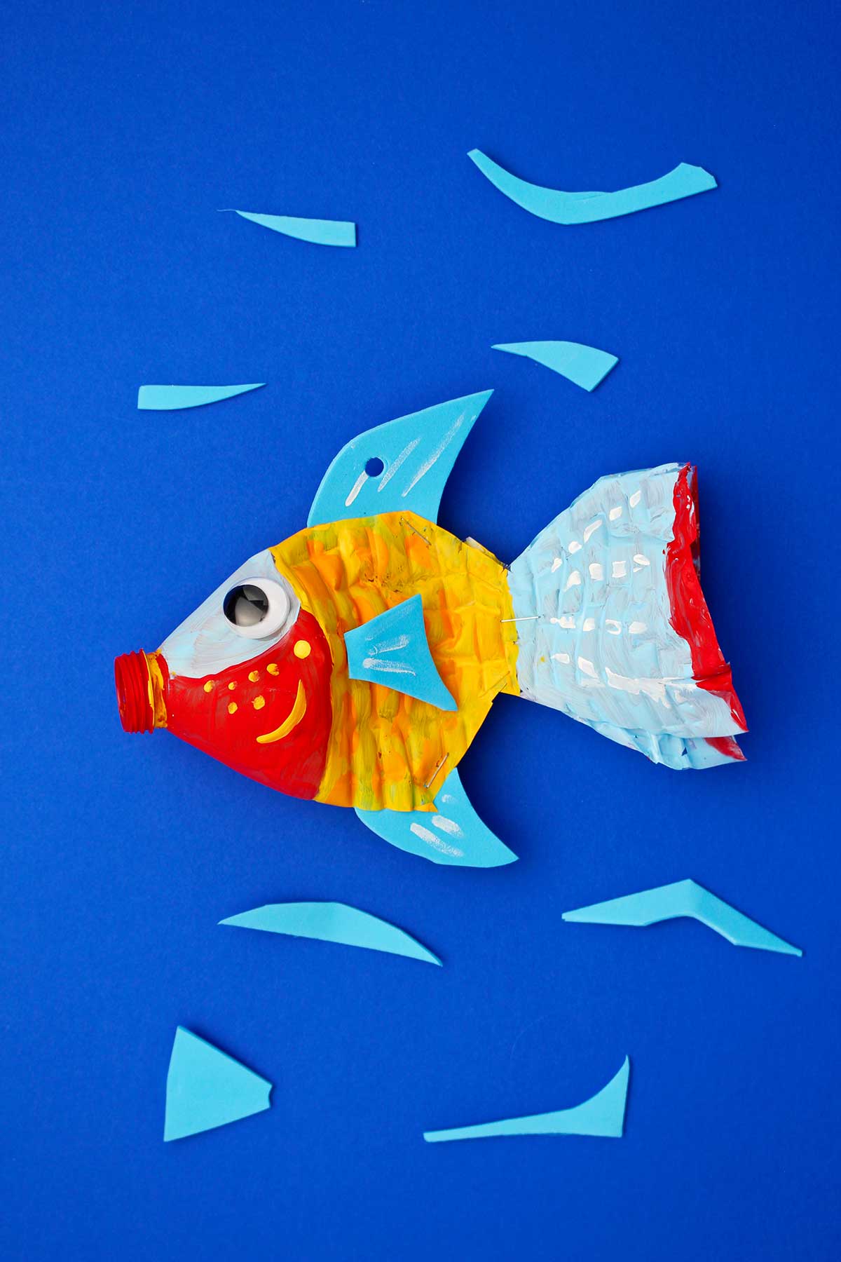 Plastic bottle fish painted red, yellow, blue and orange against a blue backdrop.