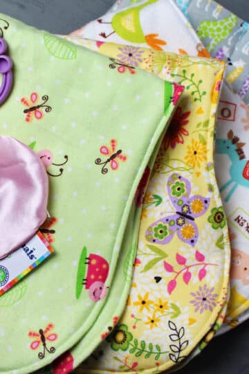 A stack of baby burp cloths made from brightly colored felt fabric prints.