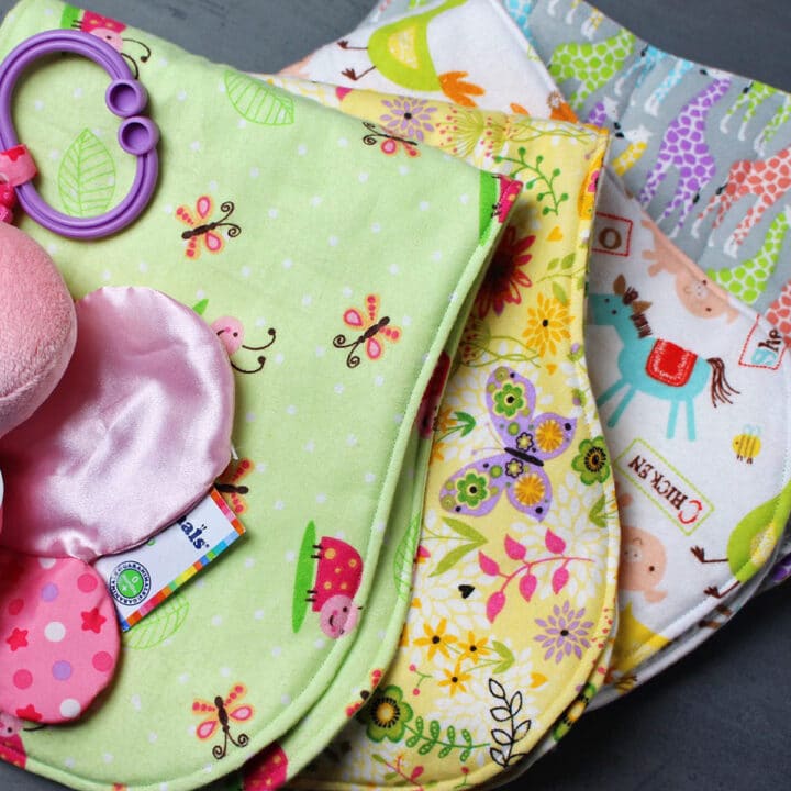 A stack of baby burp cloths made from brightly colored felt fabric prints.
