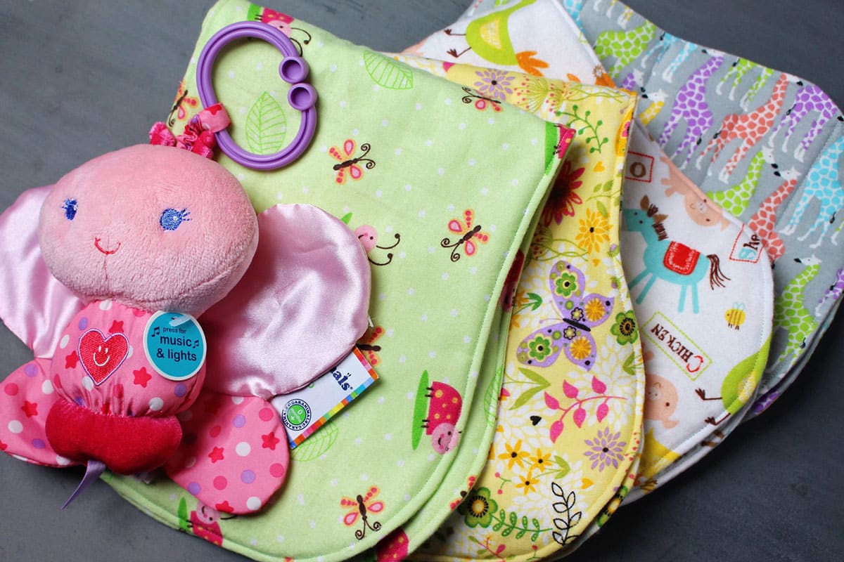 A stack of baby burp cloths made from brightly colored felt fabric prints.