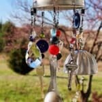 A finished whimsical DIY wind chime hanging outdoors.