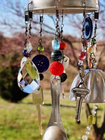 A finished whimsical DIY wind chime hanging outdoors.