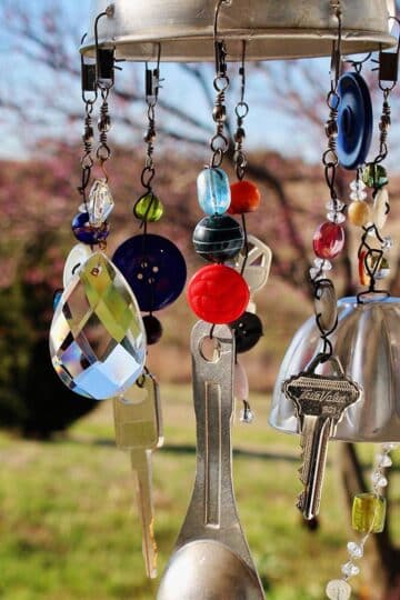 A finished whimsical DIY wind chime hanging outdoors.