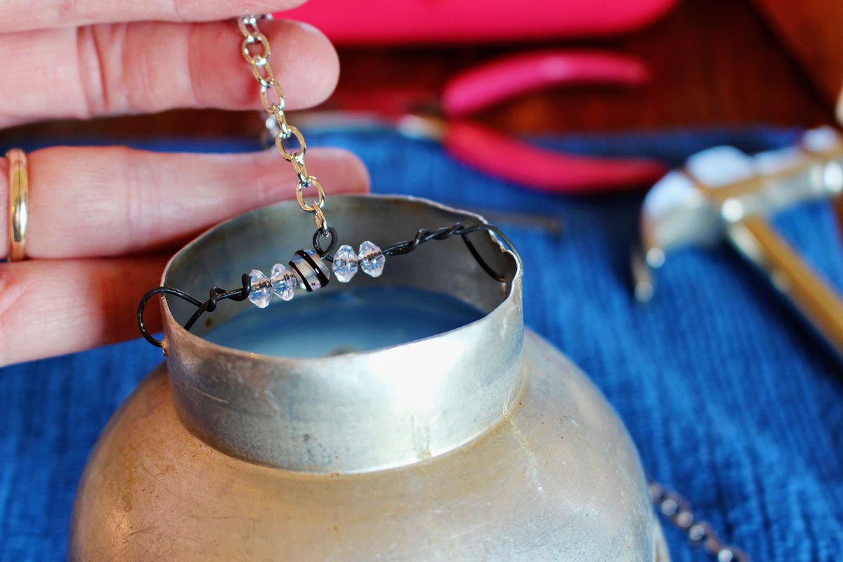 A chain and wire with beads attached to the top of a vintage funnel.