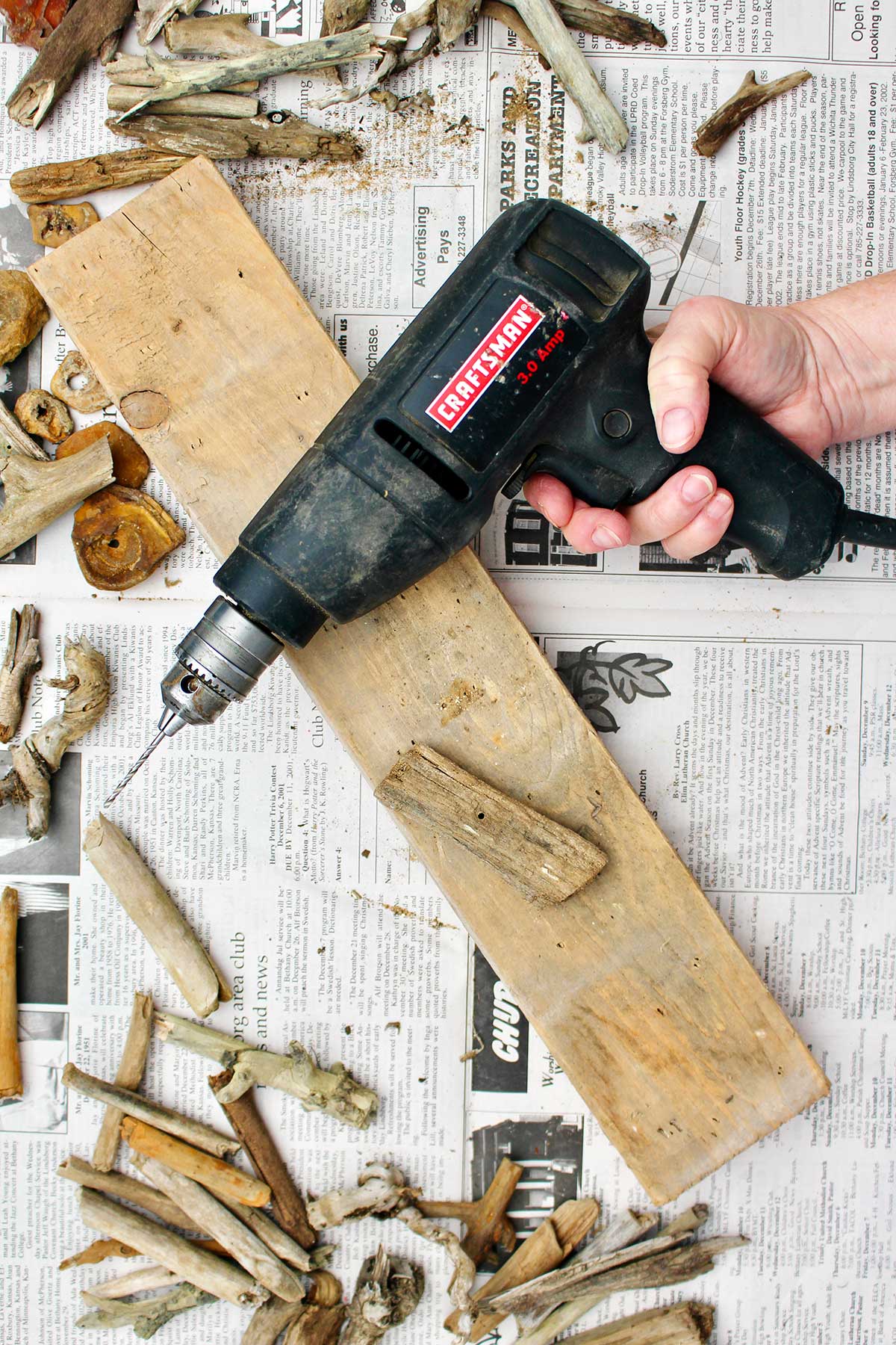 Person holding a drill after drilling a hole through the center of some driftwood.