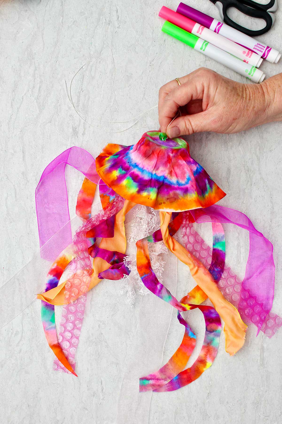 Person threading string through top of coffee filter jellyfish.