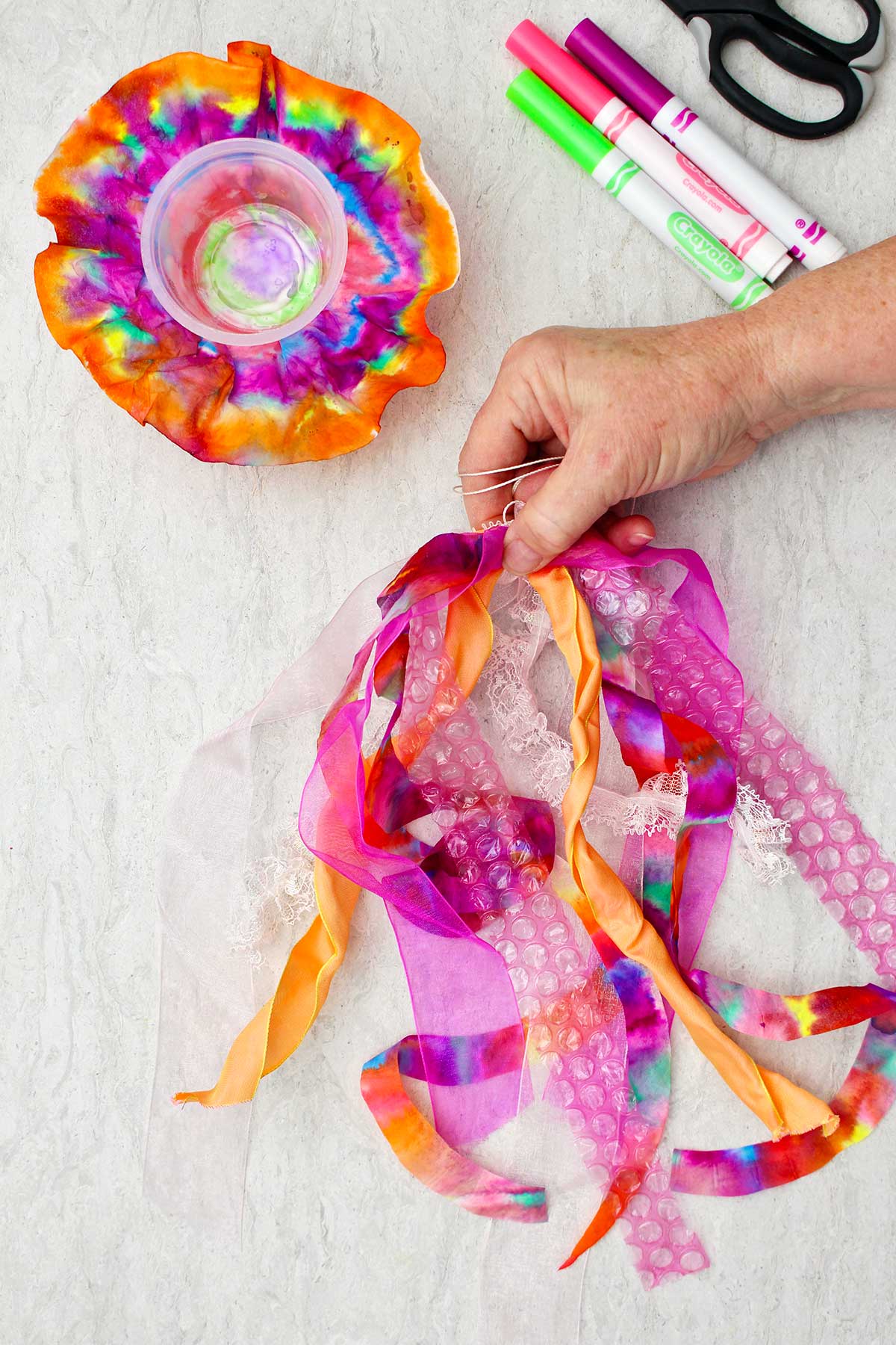 Person attaching colorful pieces of materials for bottom of jellyfish.