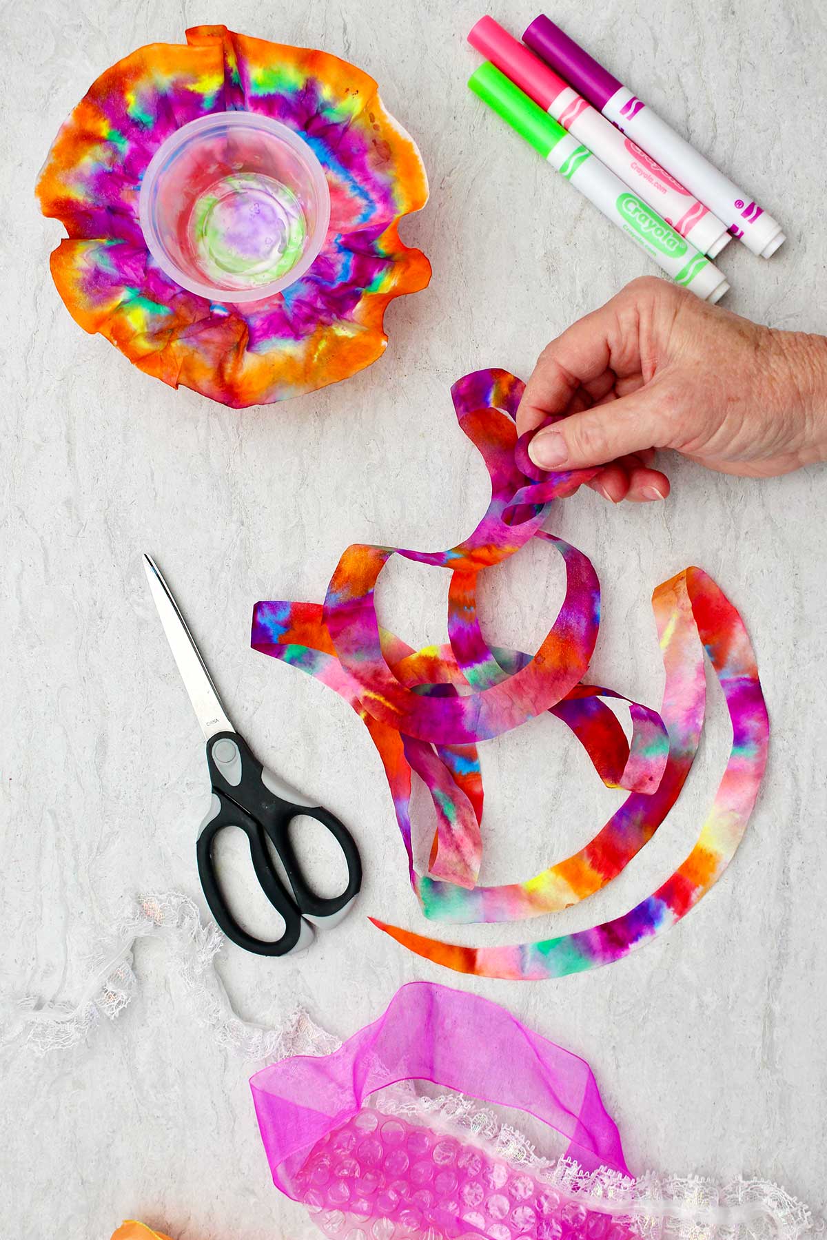 Person holding colorful cut up piece of coffee filter used for bottom of jellyfish.