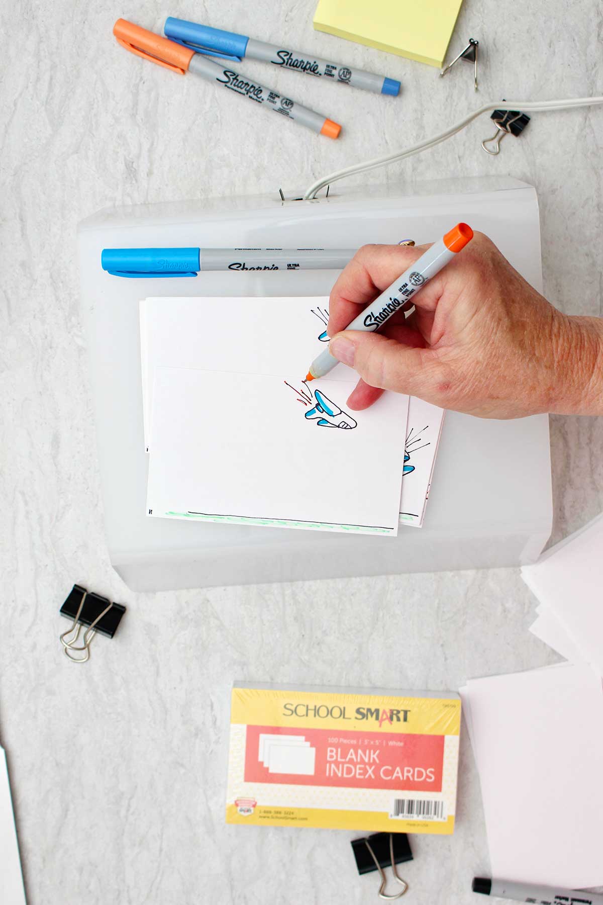 Person adding color detail to the sketches with an orange sharpie marker.