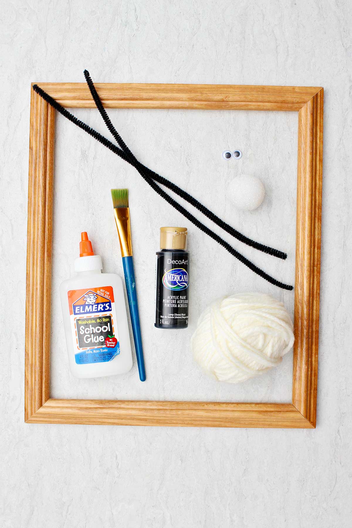 A frame, paint, paintbrush, glue, yarn and other craft supplies.