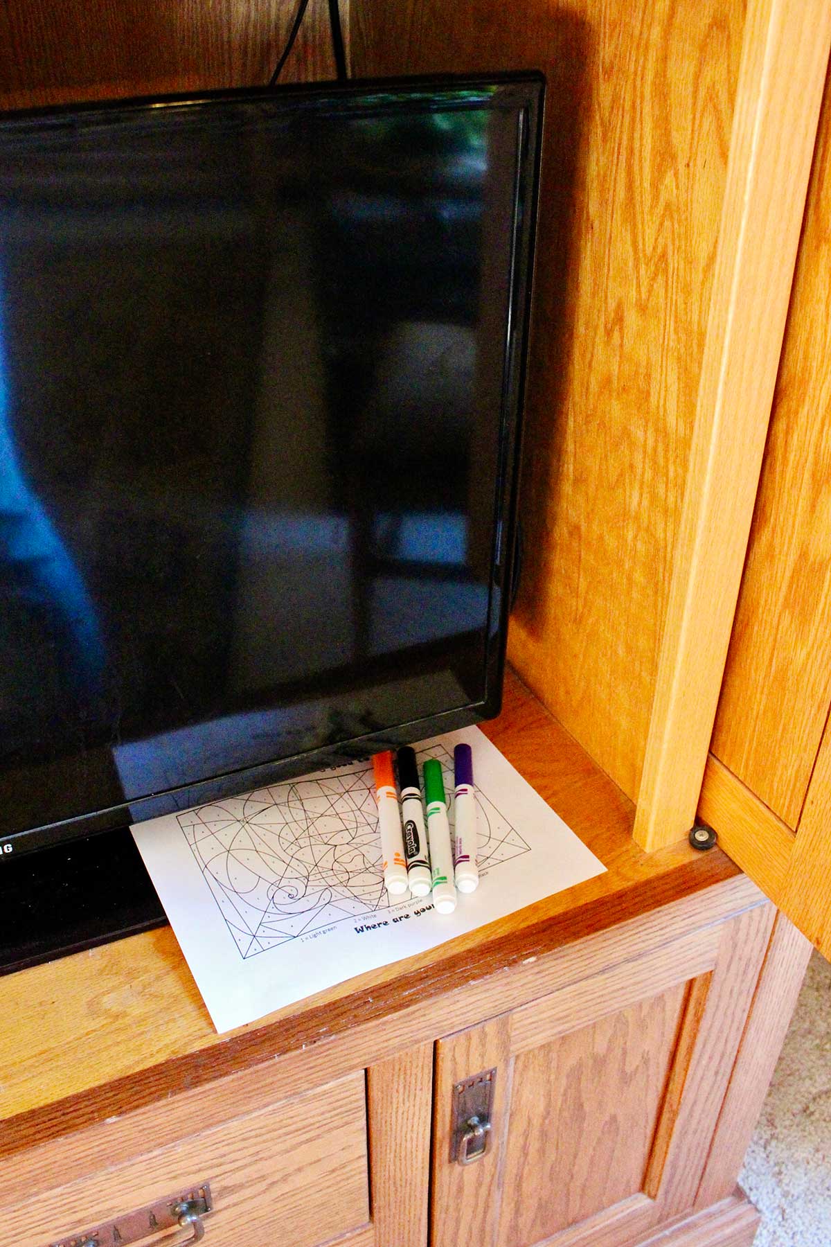 A scavenger hunt page in an entertainment center with some Crayola markers.