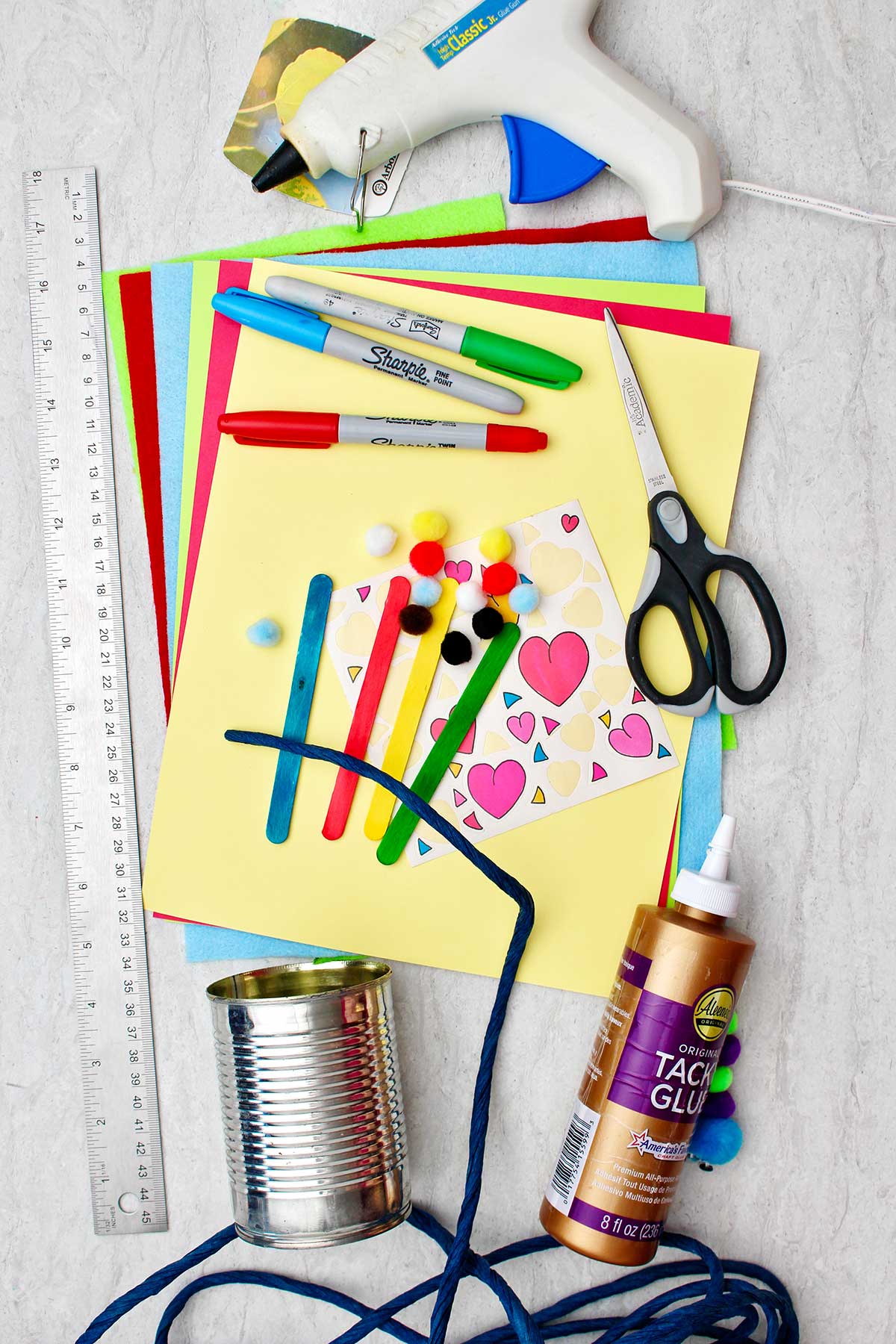 Supplies used to make pencil and pen holders. Aluminum cans, glue, colorful paper, stickers, scissors, a ruler and sharpies for decoration.