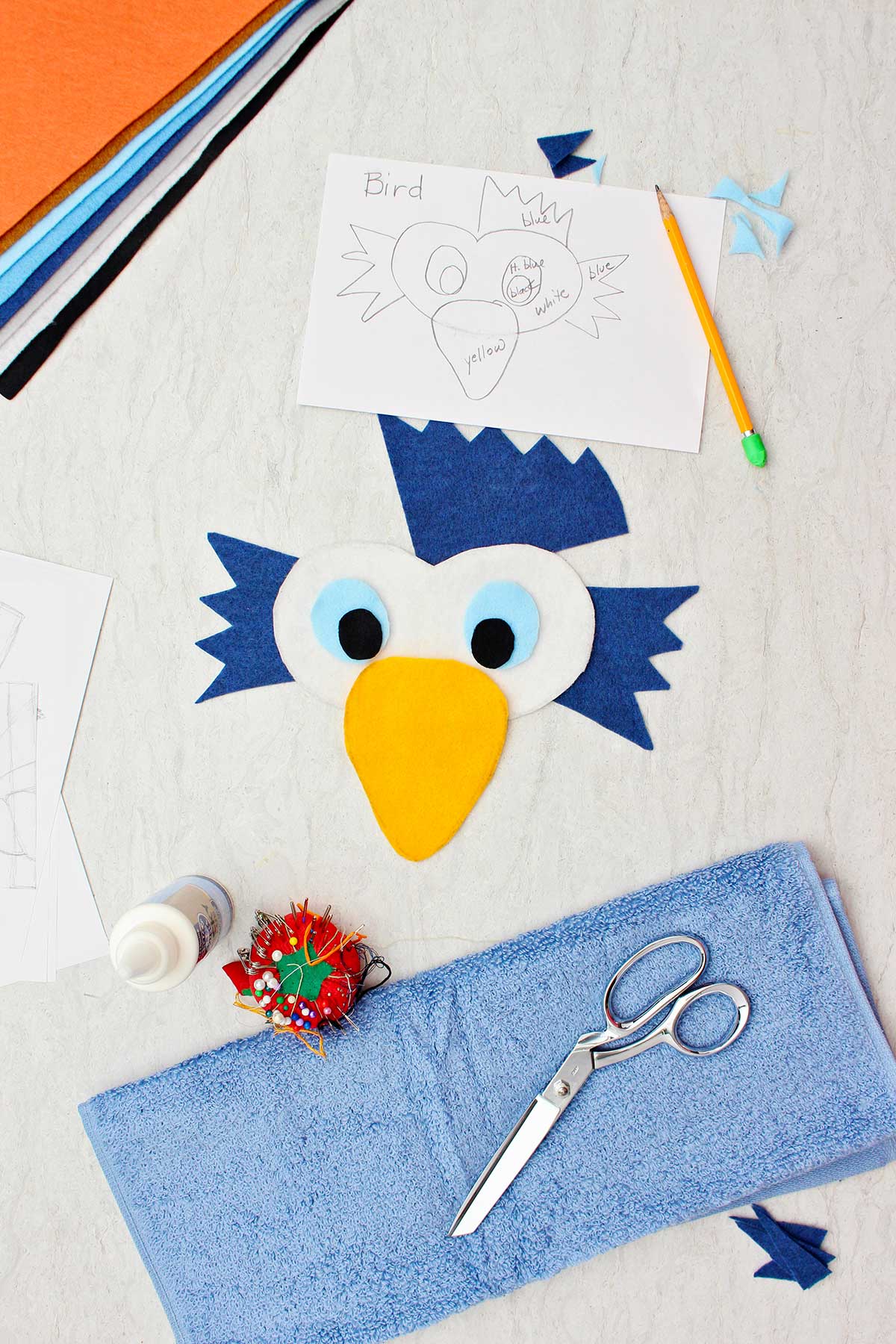 Bird face made from felt, blue terrycloth towel, scissors, pins and sketch of costume.