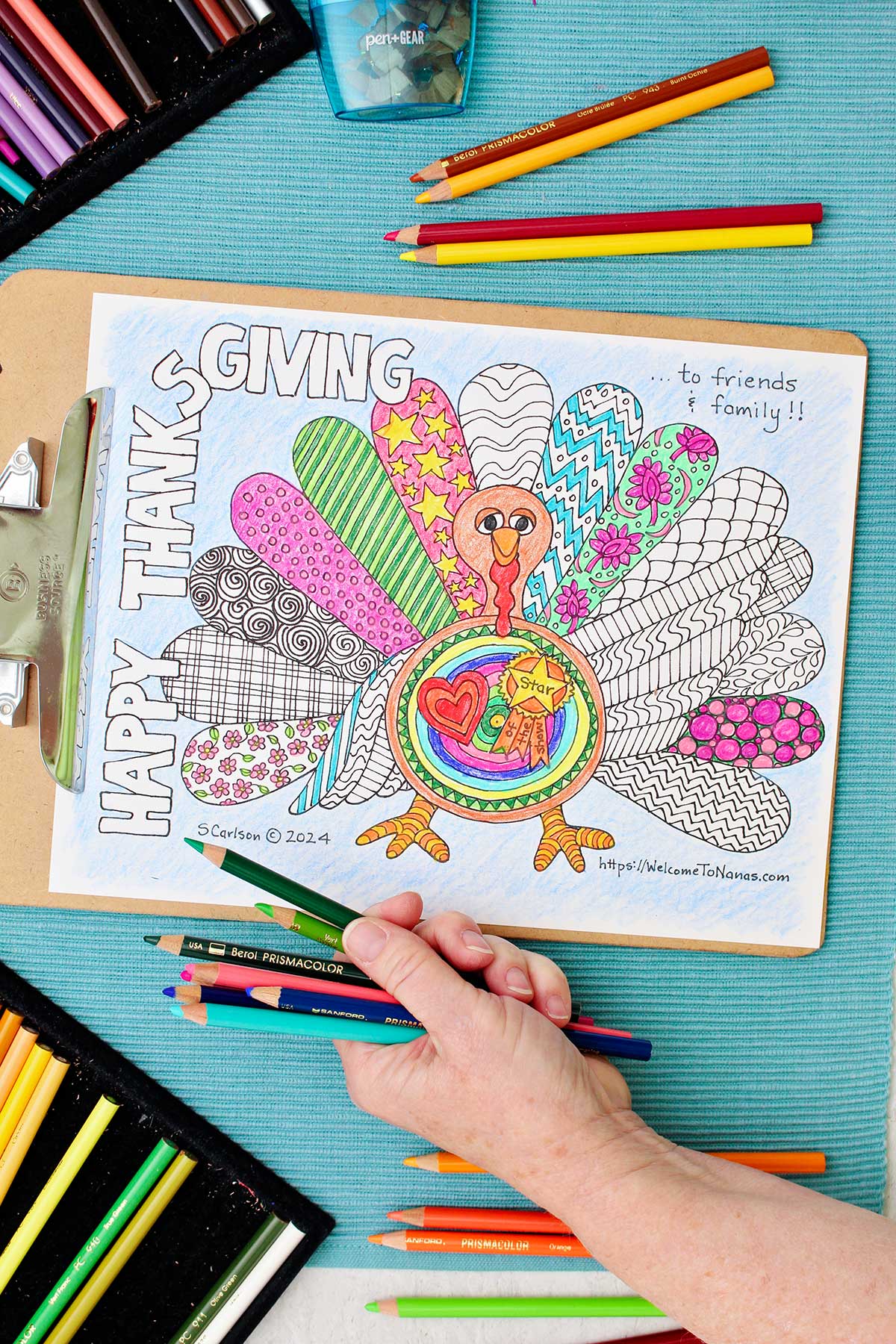 Person holding a handful of colored pencils near a partially colored in Thanksgiving coloring page.