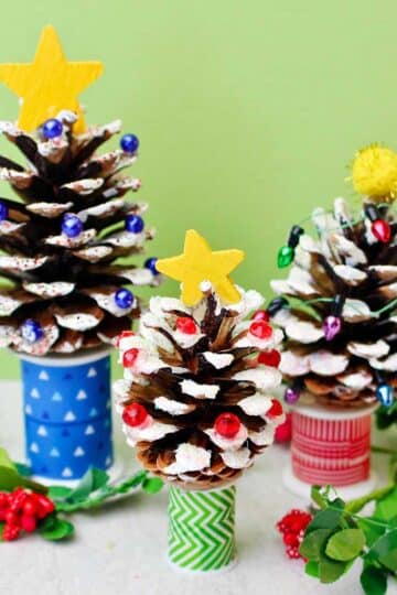 Three painted DIY Pinecone Christmas Trees with stars and bead lights