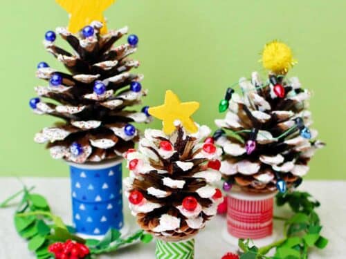 Three painted DIY Pinecone Christmas Trees with stars and bead lights