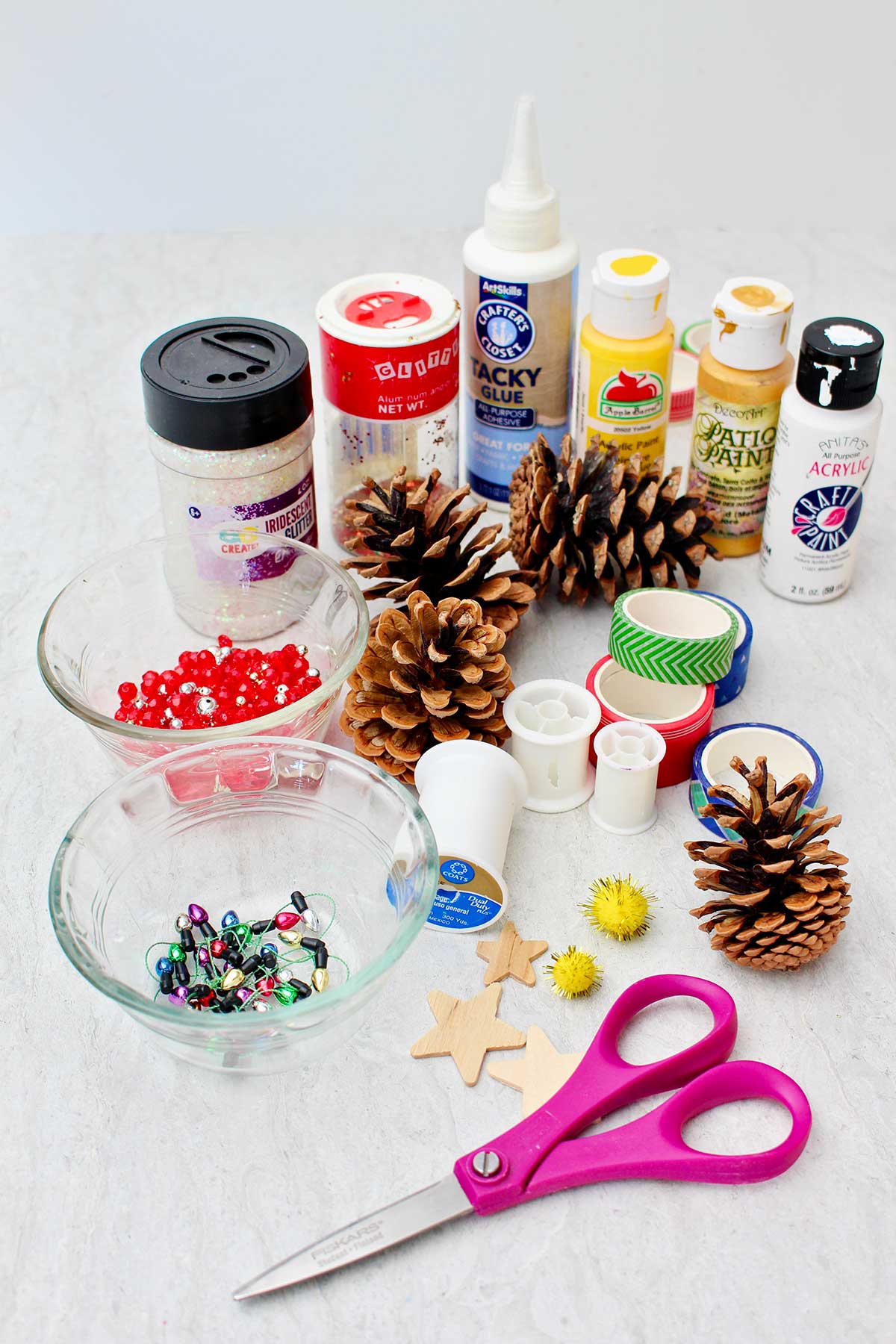 Pinecones, scissors, beads, paint, ribbons, and other craft items